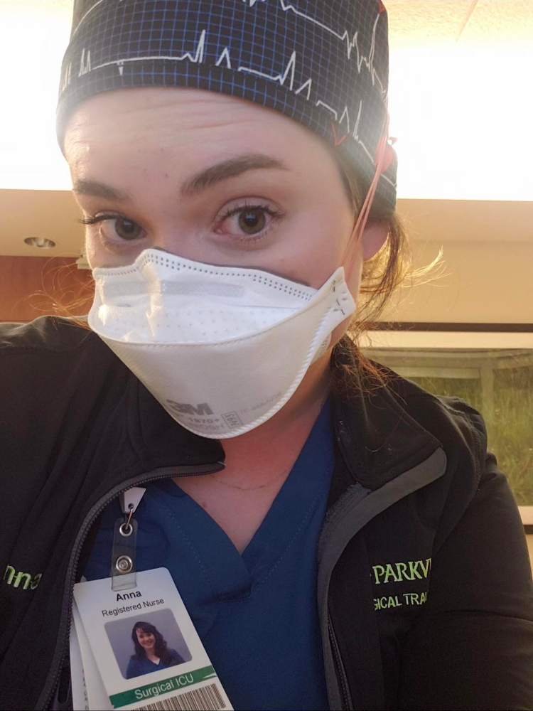 Anna Keenan in an N95 and heartbeat-print scrub cap, badge clipped to her scrubs
