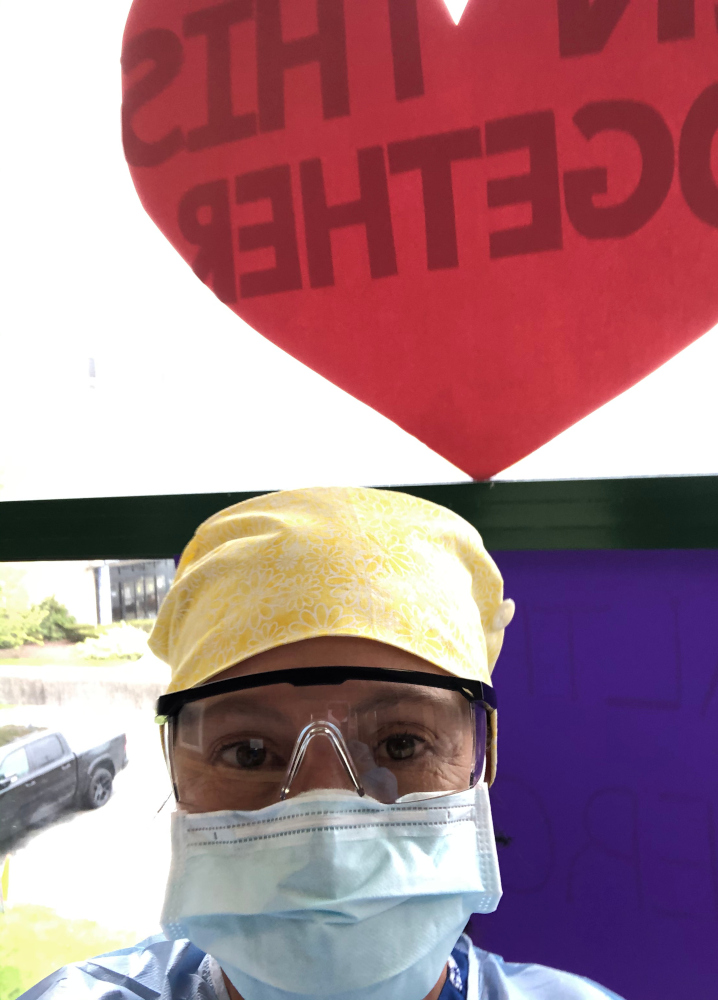 Cynthia Boyd in goggles and mask below a window heart reading "in this together"