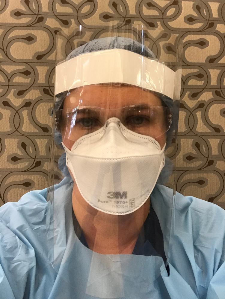 Kristen Geiger in a face shield and N95 respirator over blue scrubs