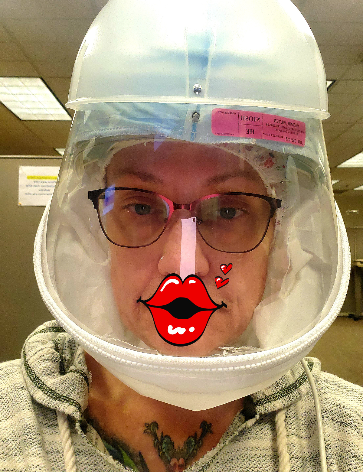 Marty Moore in a clear protective hood, with cartoon red lips stuck over her mouth