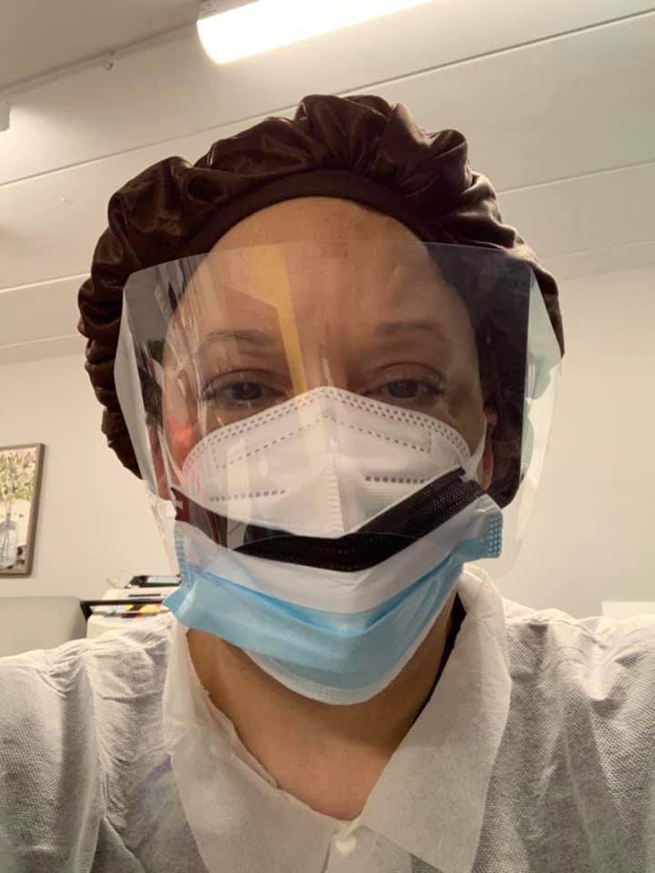 Tara Taylor in a face shield, N95 and gown, eyes smiling above her mask