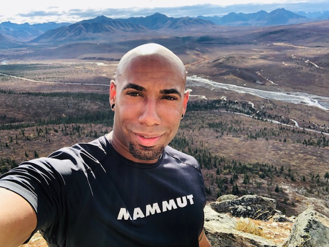 Selfie on a rocky summit above a wide river valley and mountains