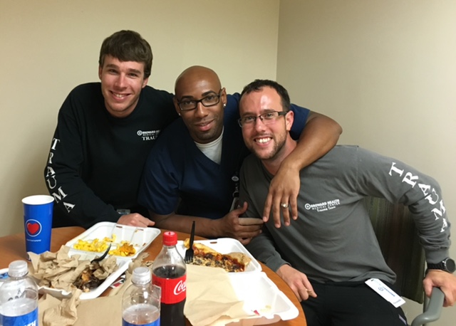 Three coworkers crowd together over a takeout meal in a break room