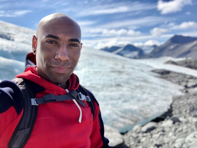 Eddie Johnson takes a smiling selfie in front of a glacier