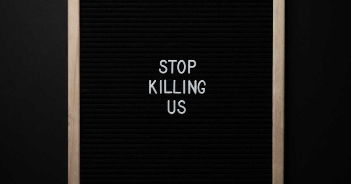 Black letter board on a wall spelling out STOP KILLING US