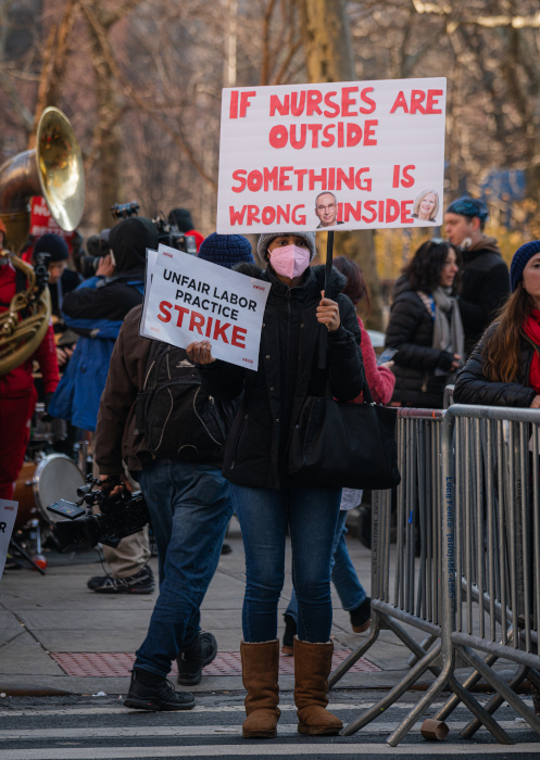 Masked picketer holds a sign: if nurses are outside, something is wrong inside