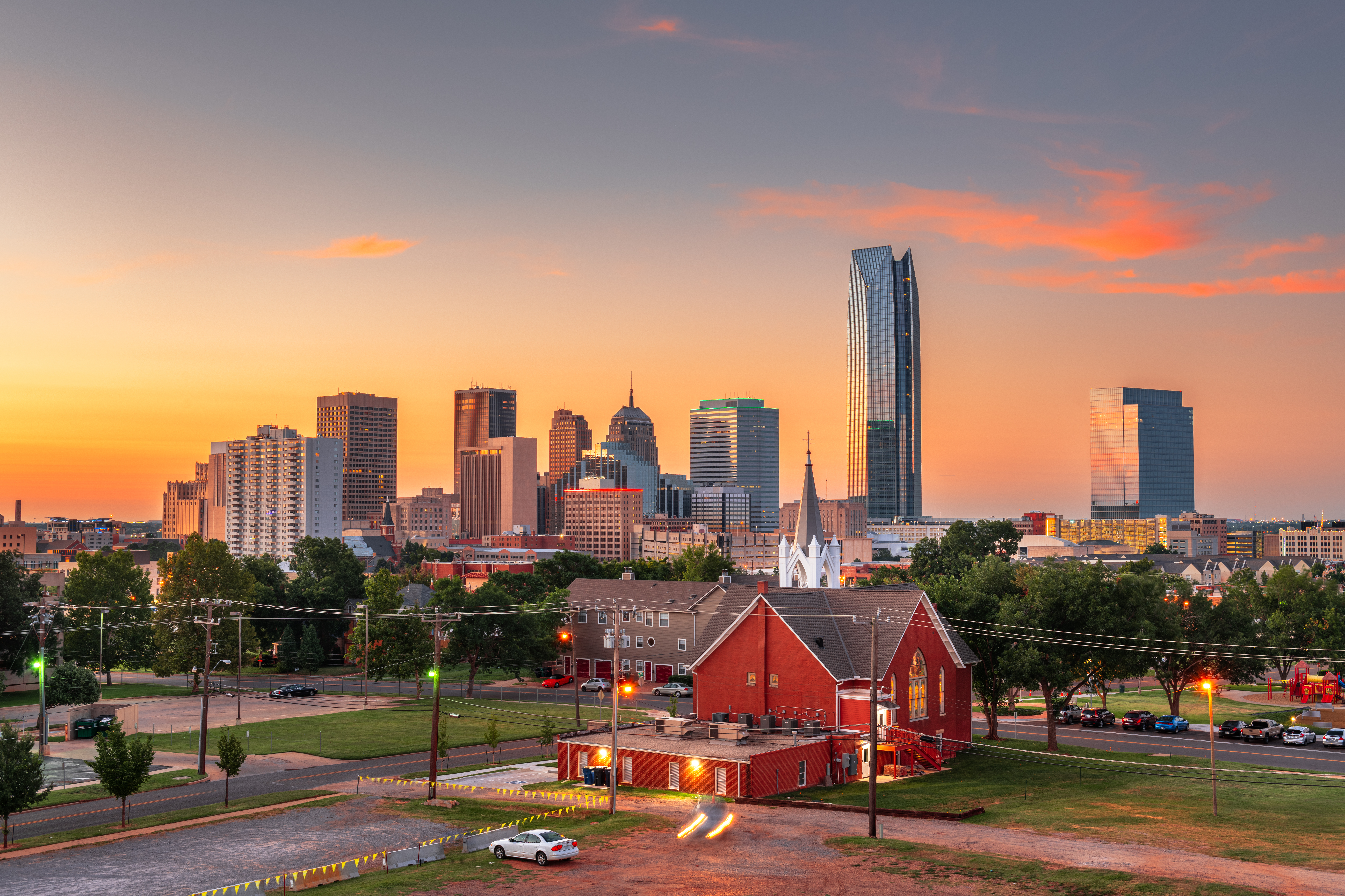 Oklahoma City skyline at sunset, seen past a red brick church
