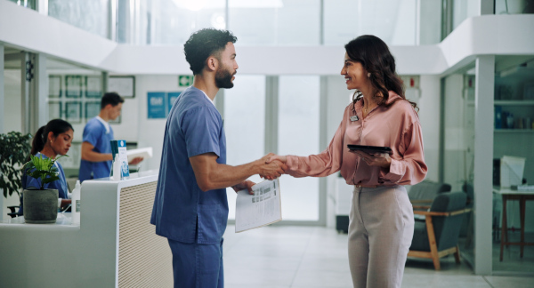 Nurse in scrubs shaking hands with a recruiter in a hospital lobby